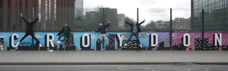 An image of young people jumping in front of an art piece showing the letters of Croydon