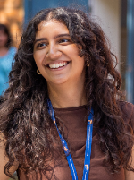Aisha Shaikh smiles, wearing a brown top