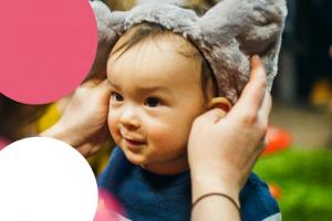 photo of a curious looking child wearing grey furry animal ears on their head
