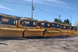 photo of seven yellow gritter lorries in a row