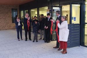 group photo including staff and pupils from Addington Valley Academy, the leader of the council Cllr Hamida Ali, and the director of education Shelley Davies, applauding at the doors to the school following a ribbon cutting ceremony