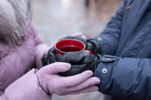 photo of two pairs of gloved hands holding a warm drink