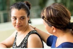 woman with a reassuring hand on another woman's shoulder