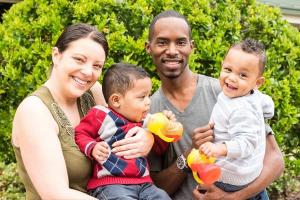 A mother and father smiling and holding their children.