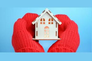 A pair of hands in mittens holding a model house