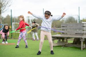 young children hula-hooping outdoors