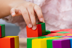 A child's hand playing with building blocks