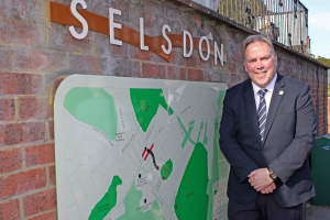 Mayor Perry standing next to a wall with Selsdon and a map attached to it.