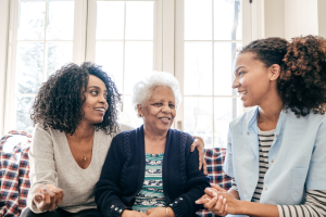 Two young women sitting with an older woman on a sofa chatting