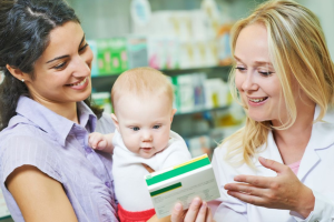 A pharmacist showing a woman and baby medication