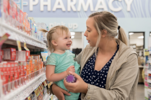 A woman holding a toddler in a pharmacy.