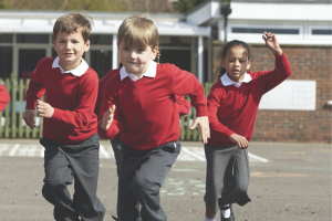A small group of schoolchildren running across a playground
