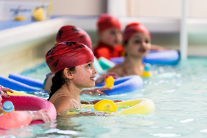 A group of children in a swimming pool with floats