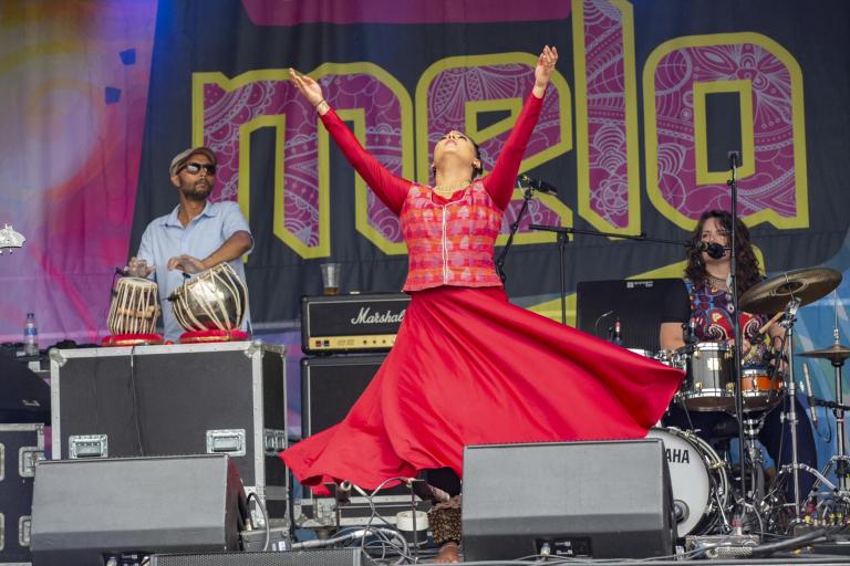 A dancer in a red dress with her arms outstretched. Photo credit: Croydon Mela.