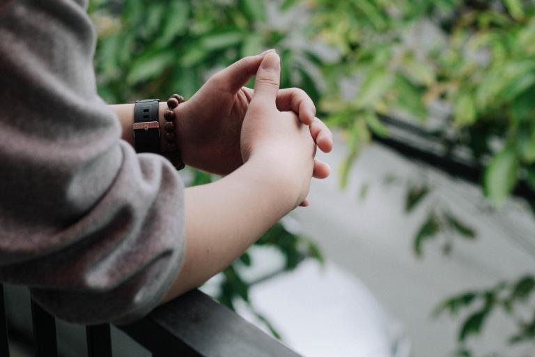 Clasped hands with greenery in the background.