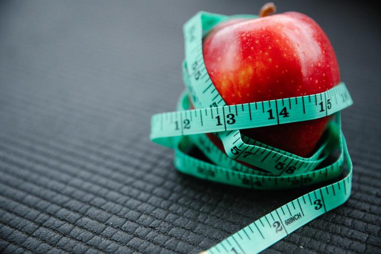 A tape measure wrapped around an apple.