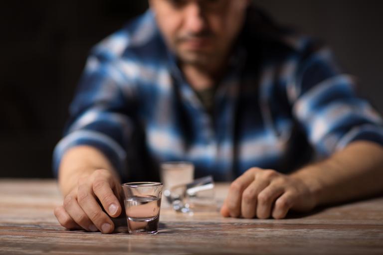 Man stares at glass of alcohol