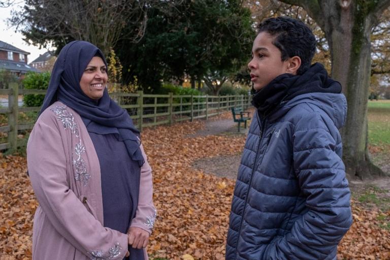 A woman and a younger person talk together outside.