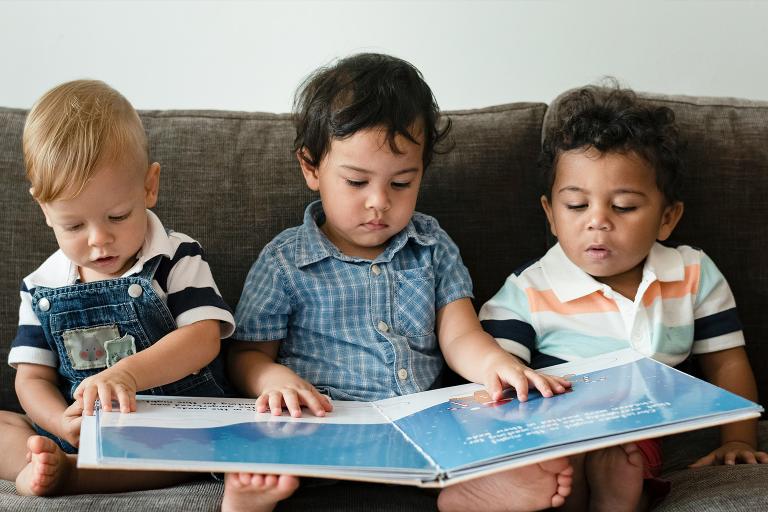 Three toddlers reading a big story book together